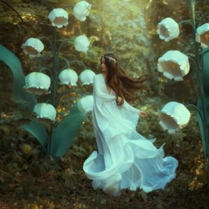 A female elf walks among the flowers in the garden.