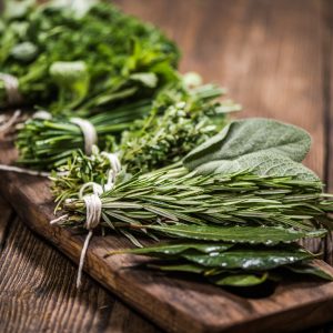 Bunches of parsley, sage, rosemary, and thyme on wooden plank