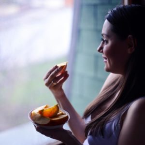 Woman eating orange in window