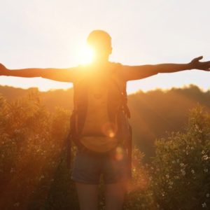 Woman hiker with arms outstretched to sun