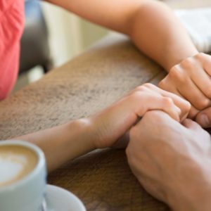 Man and woman holding hands with coffee