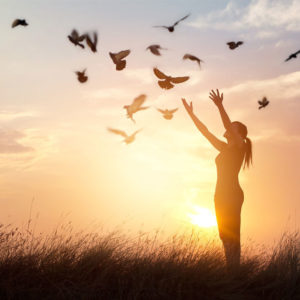 Woman releasing birds at sunset