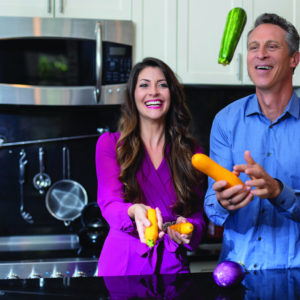 Mark Hyman and Mia Lux laughing and holding vegetables