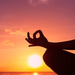 Woman meditating at sunset