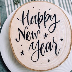 Happy New Year written on wooden place mat at table