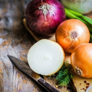 Colorful onions on wood surface