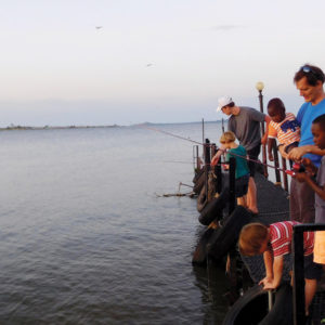 Paul Sutherland in Uganda fishing with some kids off a dock.