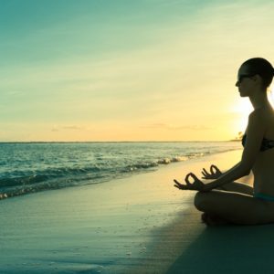 woman meditating on beach