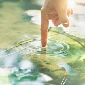 Pointer finger creating circular ripples in a pond illustrates centering prayer