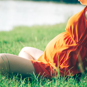 Pregnant woman sitting in grass