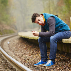 Boy sitting on train tracks