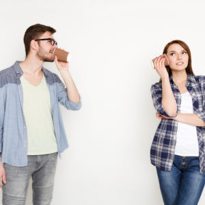 Young casual couple talking through tin can phone