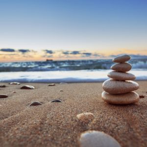 Balancing stones on beach at sunrise