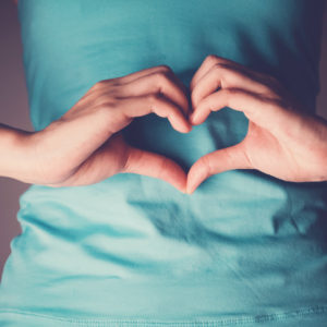 Woman making a heart shape in front of her belly