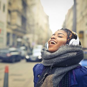 Woman walking down a city street listening to music and practicing vocal yoga