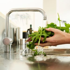 Woman washing greens at sink