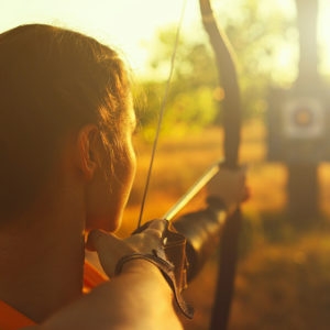 Woman with a bow and arrow aiming at bullseye target