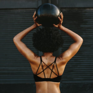 Woman holding exercise ball above her head while reciting affirmations for back pain