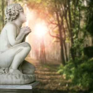 Cherub statue in forest with sun