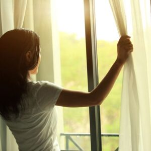 Woman looking out curtain