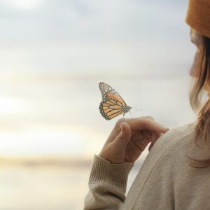 Woman with butterfly on her hand to symbolize contact your spirit guide