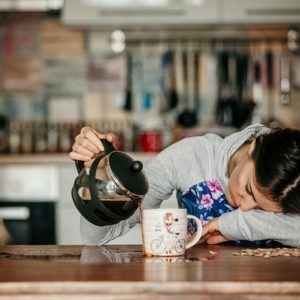 woman spilling coffee because of exhaustion coaxing adrenals