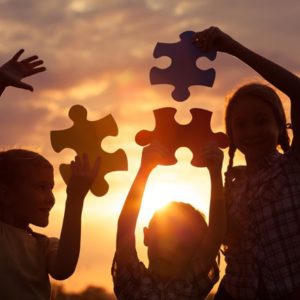 Kids and puzzle pieces at sunset