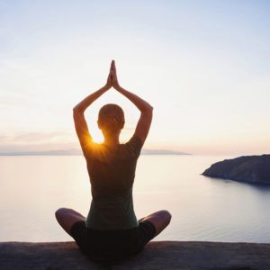 A woman outside at sunset doing yoga practicing psychic protection