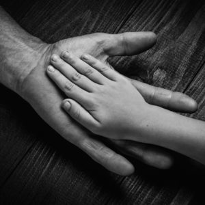 Hands of elderly man holding younger hand