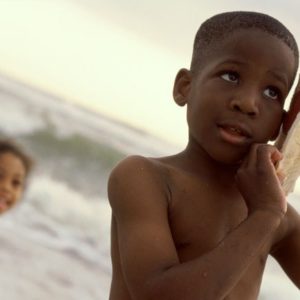 Boy listening to conch shell at ocean