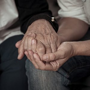 An elderly couple holding hands and being present