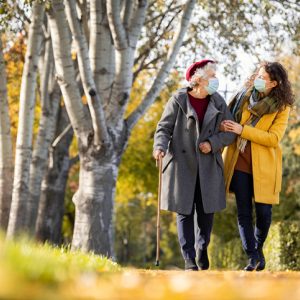 Two women walking in park wearing face masks