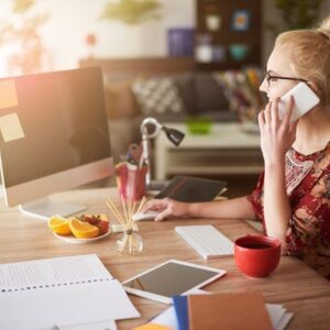 Woman at desk, on phone looking at computer