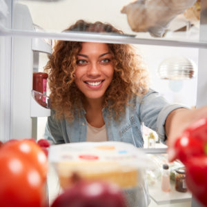 woman reaching into refrigerator to clean it out