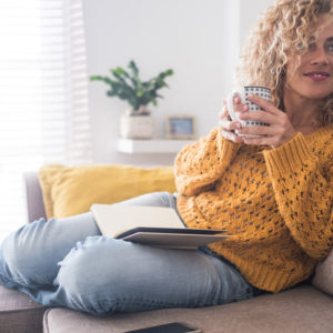 A woman drinks tea on her couch