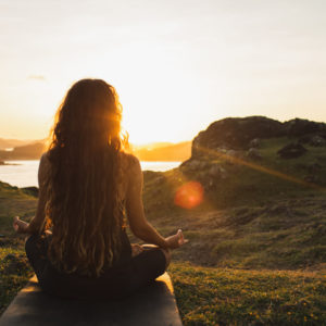Woman meditating alone at sunrise in the mountains