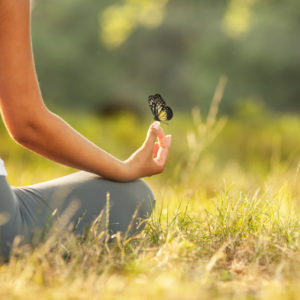 Woman meditating with butterfly landing on hand