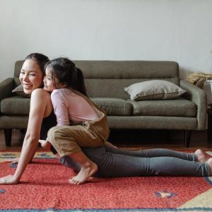 Mother doing yoga with daughter on back yoga for caregivers