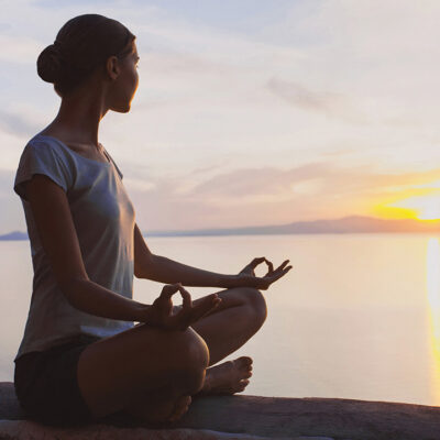 woman meditating by a lake