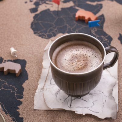 A mug of ethical hot chocolate sits on a map of the world with animal figures.