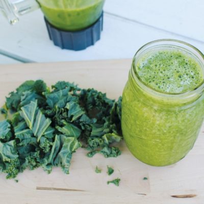 Green smoothie and kale on wood surface