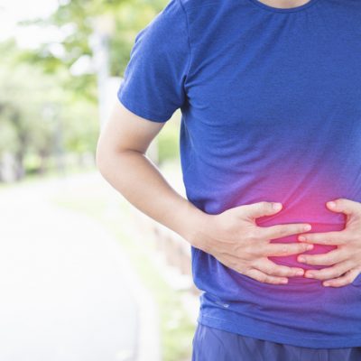 Man with an inflamed gut doubles over in pain, illustrating how CBD can help with stomach issues