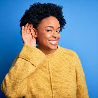 Woman smiling holding ear to listen with empathy