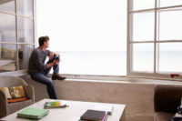 Man, isolated, looks out onto the water from his window