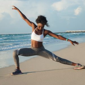 black woman doing yoga on beach