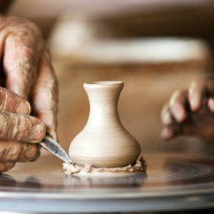 Two hands working on clay wheel