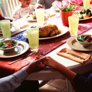 Family holding hands around dinner table