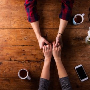 Couple holding hands with coffee at table