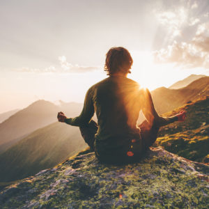 Man meditating yoga at sunset in the mountains