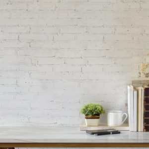 Marble desk with books, coffee mug, mobile phone and plant